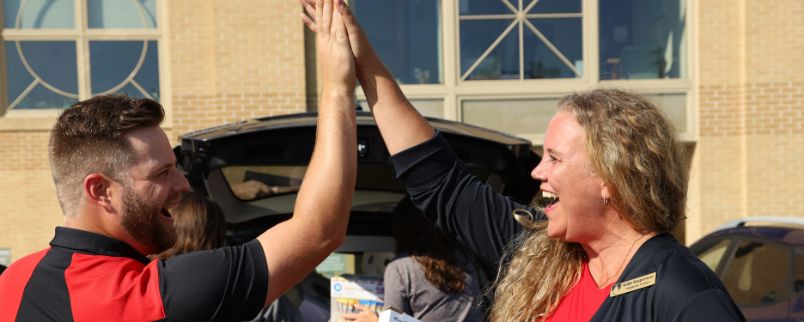 Two Edgewood College staff high-fiving one another.