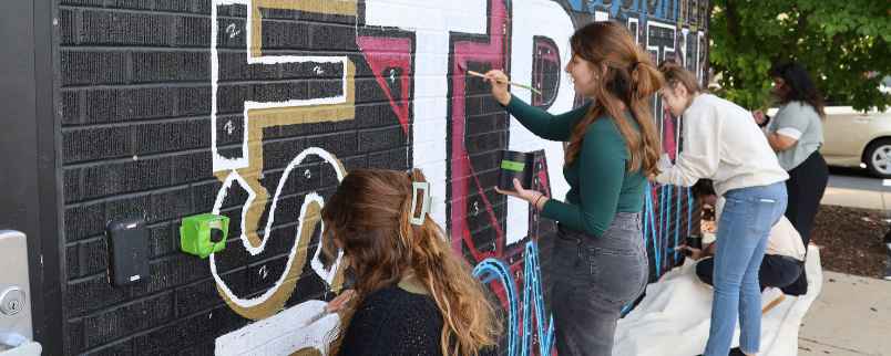 Edgewood College students painting the campus’ Values mural.
